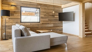 Un interior moderno con una pared de madera, un sofá, un televisor y una escalera.