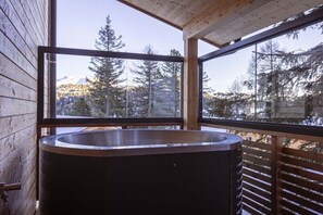 Una cabaña de madera con un ventanal grande y un jacuzzi.