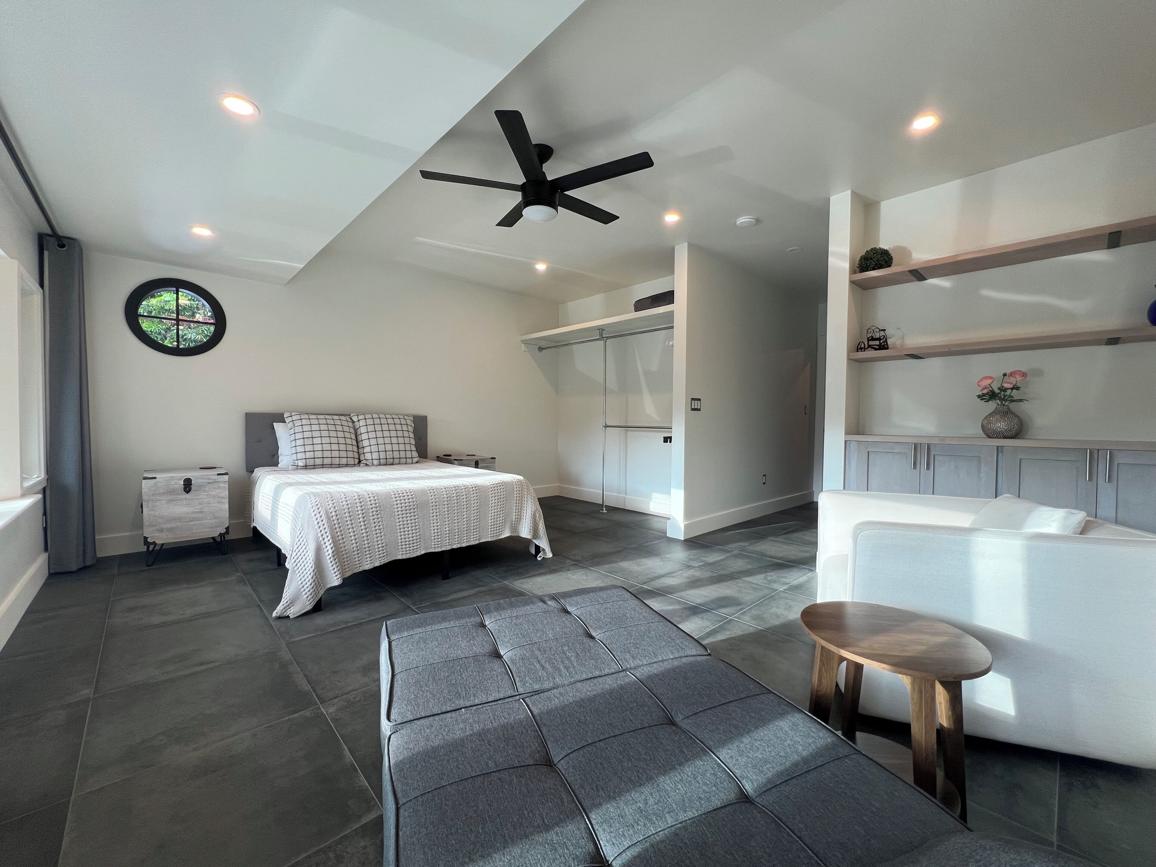 A modern bedroom with a bed, bedside table, and a ceiling fan.