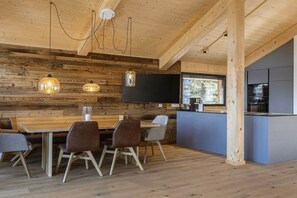 A modern kitchen with a large island, wooden walls, and pendant lighting. - Superior Chalet #1 with Sauna & Hot Tub (Turrach)
