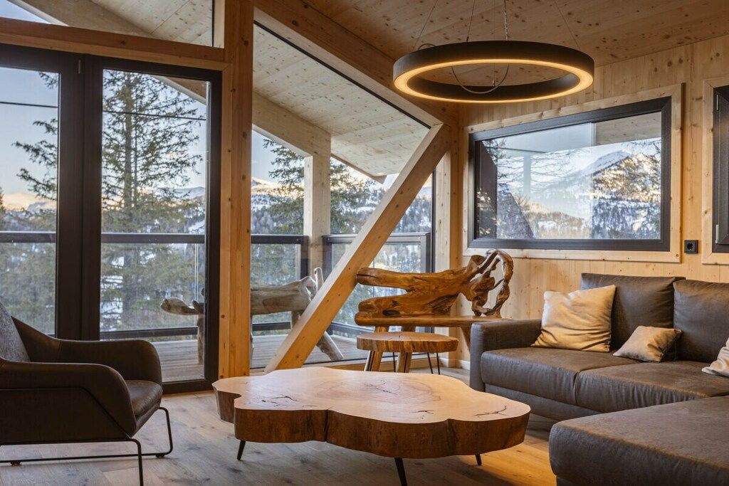 A modern interior with a wooden ceiling, large windows, a wooden coffee table, and a sofa.