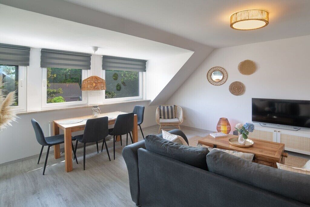 En moderne stue med spiseplads, en sofa, et fjernsyn og en loftlampe.