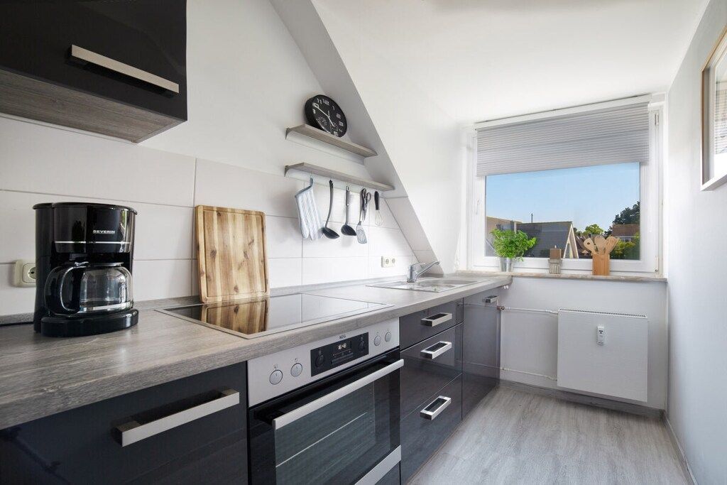 Una cocina moderna con horno empotrado, cafetera y ventana con vistas al exterior.