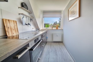 Eine moderne Küche mit einer Holz Arbeitsplatte, Edelstahlgeräten und einem Fenster mit Blick auf Grünflächen.