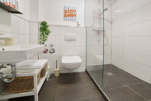 A modern bathroom with a glass shower enclosure, a white sink, and a toilet. - Holiday apartment with 2 bedrooms (Heiligenhafen)