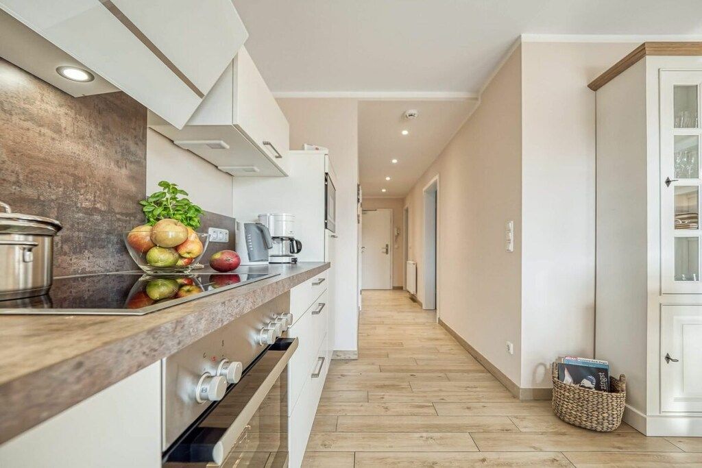 Cocina moderna con encimera de madera, electrodomésticos de acero inoxidable y vista al área de estar contigua.