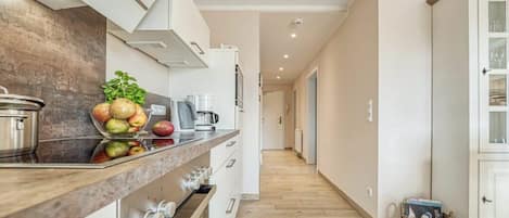 Cocina moderna con encimera de madera, electrodomésticos de acero inoxidable y vista al área de estar contigua.