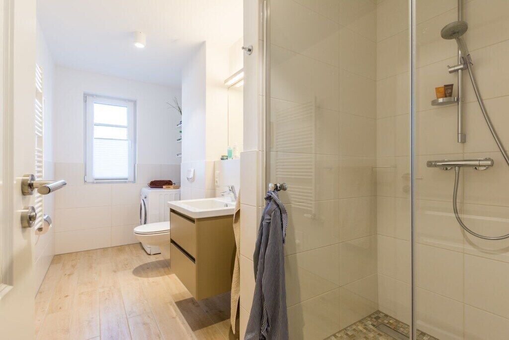 Une salle de bain avec une douche à parois de verre, un lavabo, des toilettes et une fenêtre.