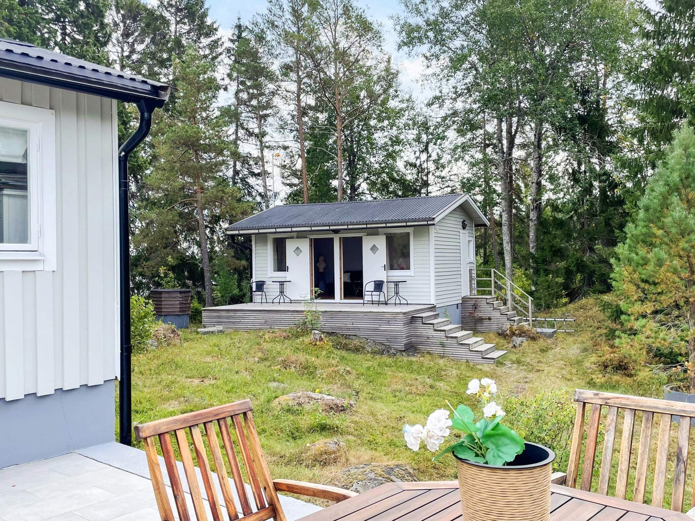 Ein kleines Häuschen mit Veranda, Sitzgelegenheiten im Freien und einem Garten.