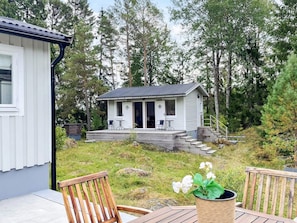Ein kleines Häuschen mit Veranda, Sitzgelegenheiten im Freien und einem Garten.
