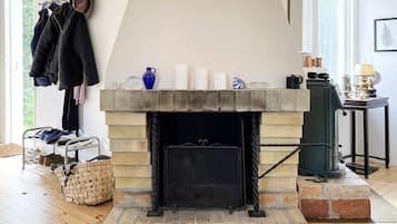 A fireplace with a mantel, a shoe rack, and a basket on the floor.