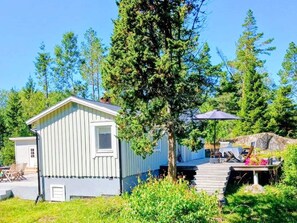 Eine kleine, einstöckige Holzhütte mit Veranda und einem Tisch mit Sitzgelegenheit im Freien.