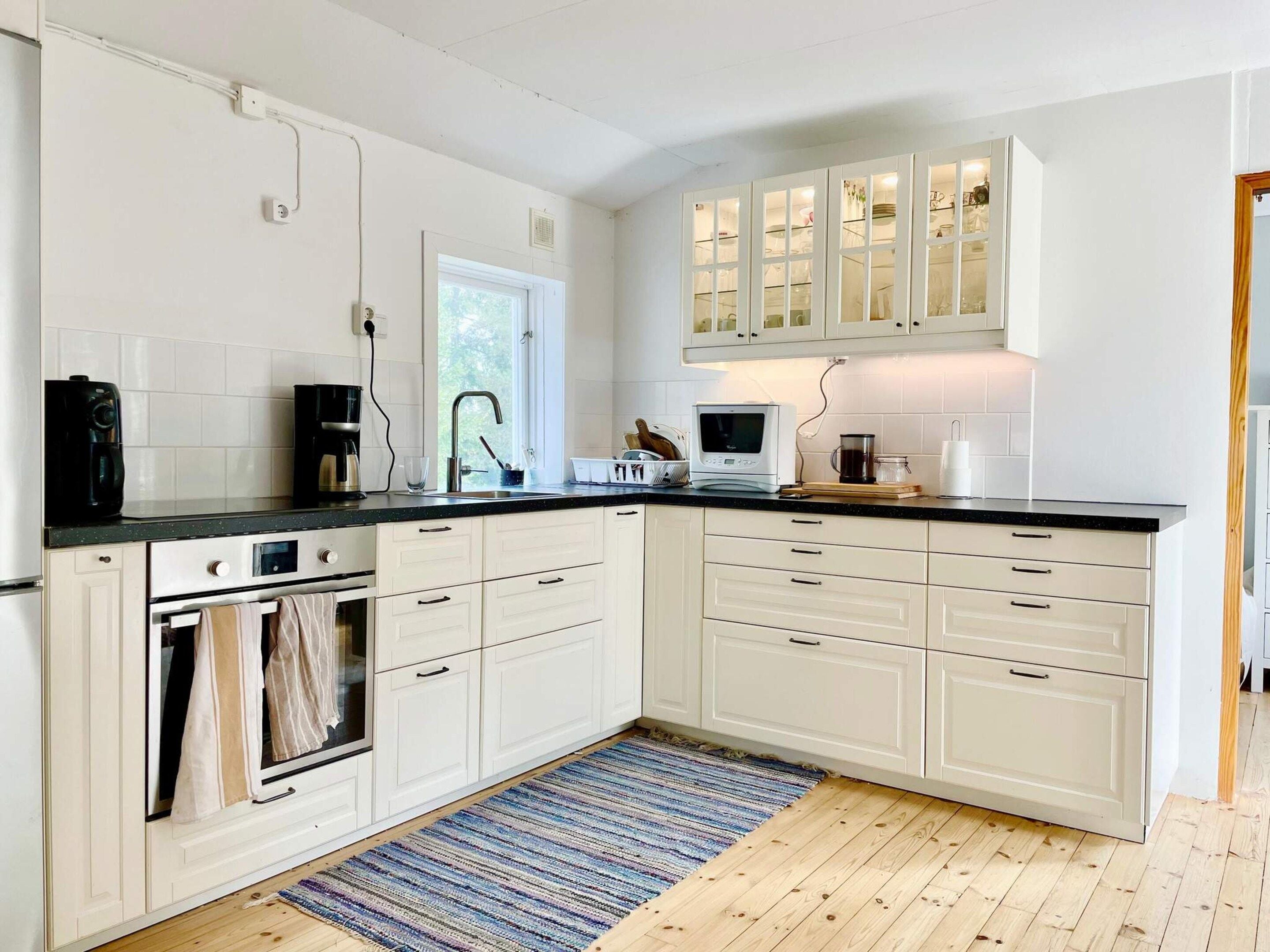A kitchen with white cabinets, a black countertop, a built-in oven, a microwave, and a coffee maker.
