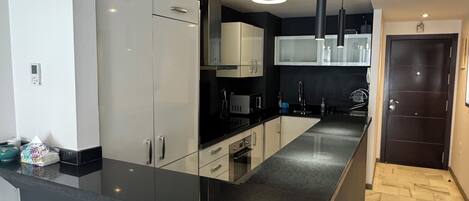 A modern kitchen with a central island, built-in appliances, and a dark countertop.