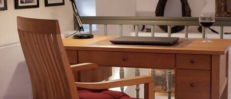 A wooden desk with a laptop, a lamp, and a wine glass.
