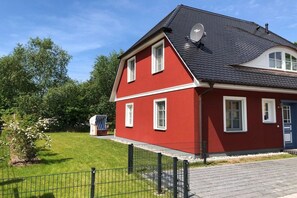 A red two-story house with a dark roof, white windows, and a blue door. - Holiday home with 3 bedrooms (Ostseebad Prerow)