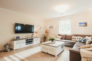 A living room with a flat-screen TV, a sofa, a coffee table, and a window. - Holiday home with 3 bedrooms (Ostseebad Prerow)