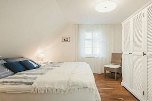 A bedroom with a bed, a chair, and a wardrobe. - Holiday home with 3 bedrooms (Ostseebad Prerow)
