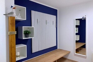 A modern interior with a blue accent wall, white shelving units, a wooden bench, and a vertical white panel. - Park Residence at Hafen 11 - "MeerZeit" (Seeheilbad Zingst)