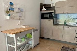A compact kitchen with a built-in oven, a small sink, and a pegboard wall with various items. - Park Residence at Hafen 11 - "MeerZeit" (Seeheilbad Zingst)