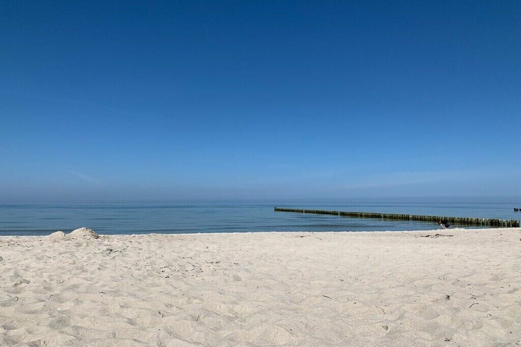 Une plage avec une jetée en bois qui s’avance dans l’eau.