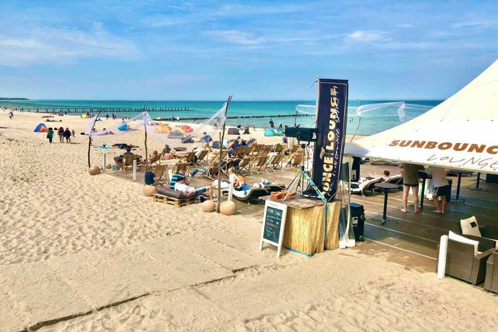 Uma área de estar à beira-mar com espreguiçadeiras e uma placa.