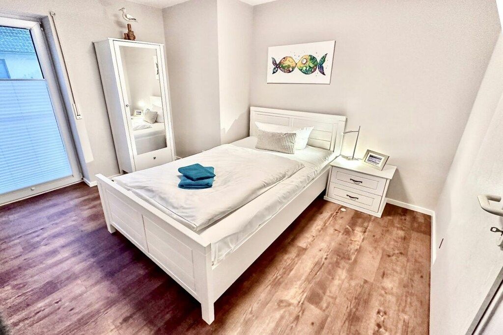 A bedroom with a bed, bedside table, nightstand, and a mirror.