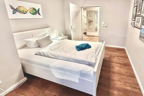 Een slaapkamer met een bed, nachtkastje en een kunstwerk aan de muur.