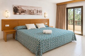 Een hotelkamer met een groot bed, een nachtkastje, een wandlamp en een raam met gordijnen.