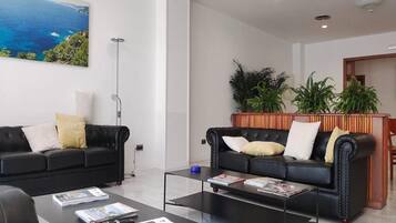 Een moderne woonkamer met twee zwarte leren banken, een salontafel en een boekenkast.