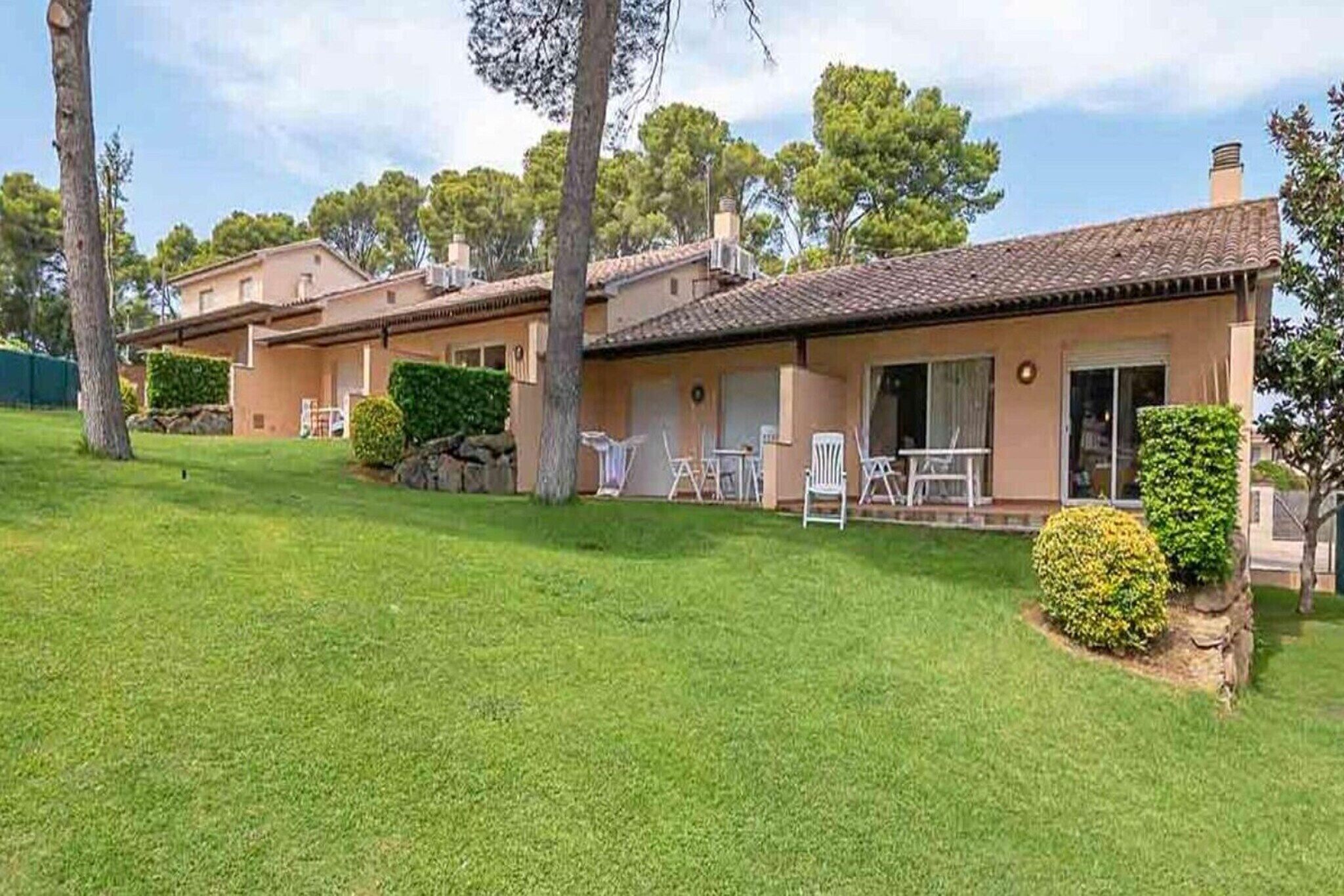 A two-story house with a tiled roof, a front lawn, and a small garden area.