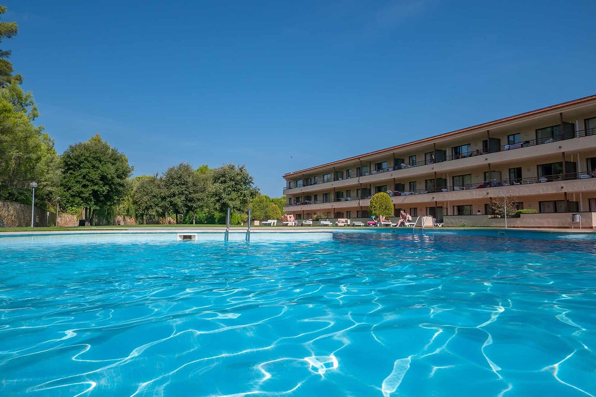 Un hotel con piscina, varios balcones y fachada.