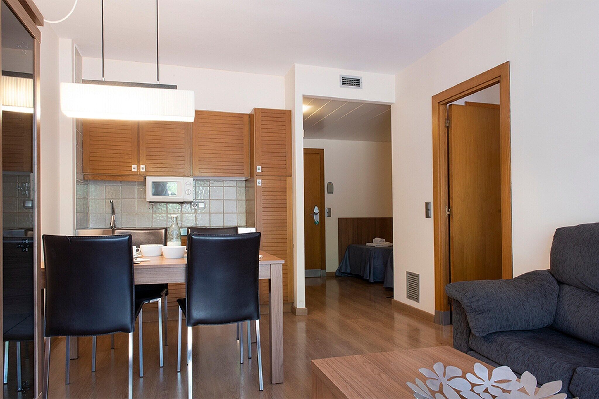 Una cocina moderna con armarios de madera, una mesa de comedor con sillas y un área de estar con un sofá.