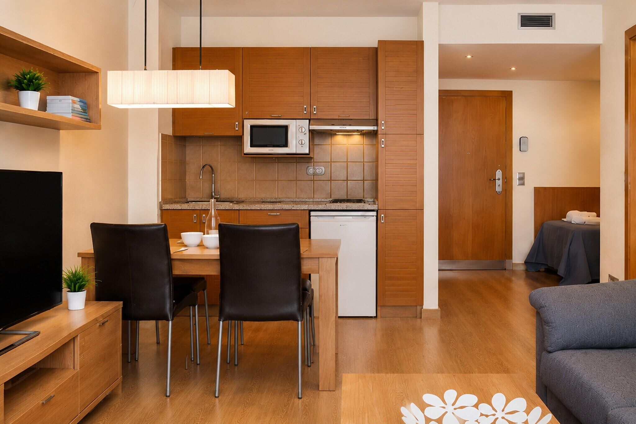 Une cuisine moderne avec des meubles en bois, un four à micro-ondes et un coin repas comprenant une table et des chaises.