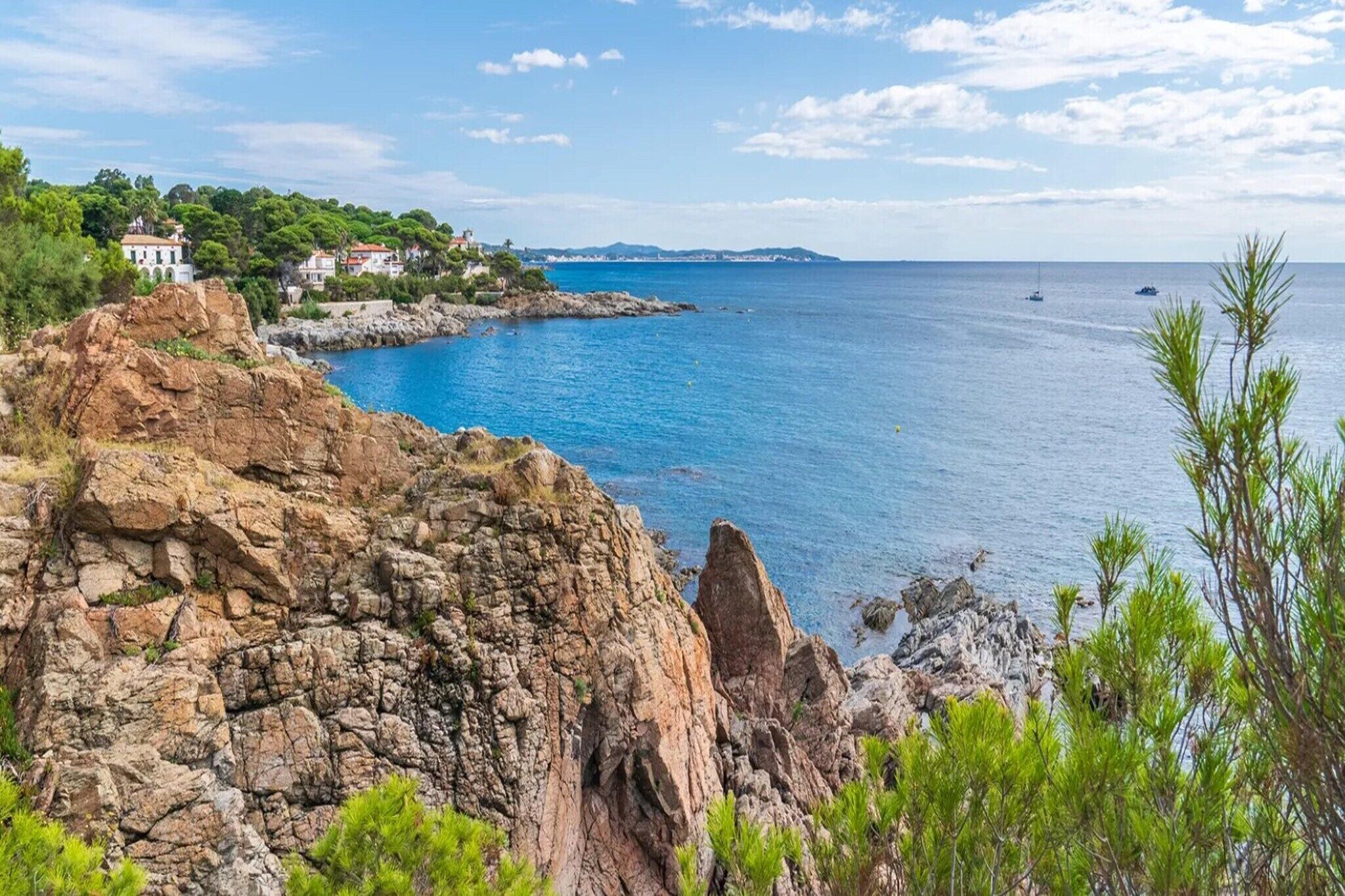 A coastal landscape with rocky terrain, a body of water, and a building with a white facade.