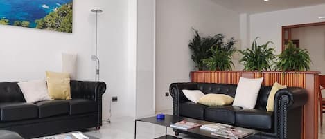 Una sala de estar moderna con dos sofás de cuero negro, una mesa de centro y una estantería.