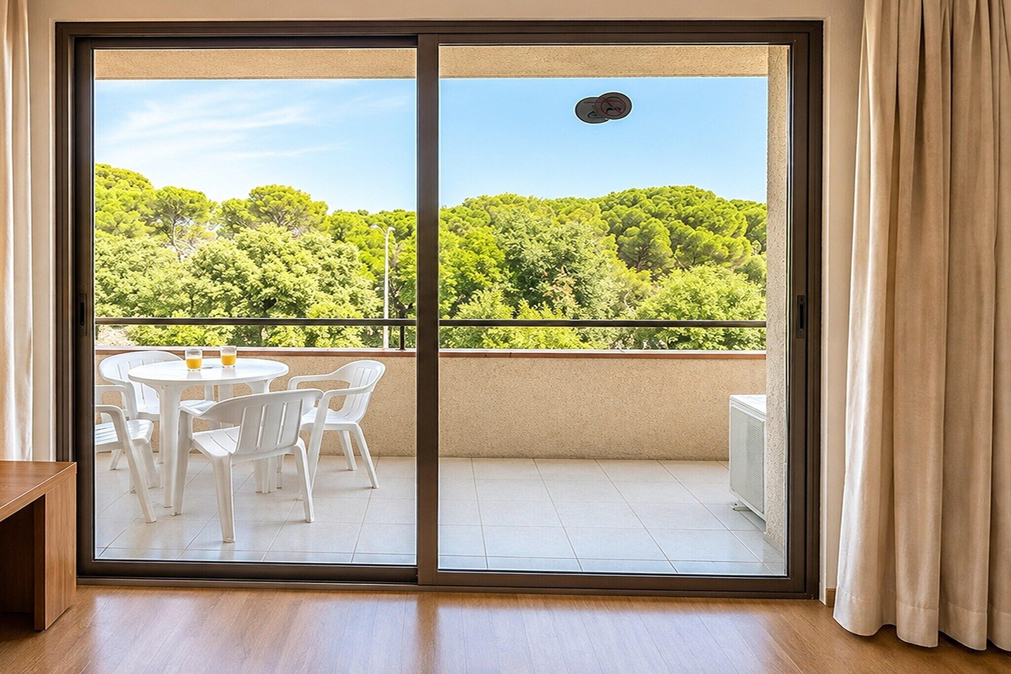 Une pièce dotée d’une porte-fenêtre coulissante qui donne sur un balcon extérieur offrant une vue sur un paysage verdoyant.