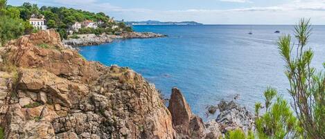 A coastal landscape with rocky terrain, a body of water, and a building with a white facade.