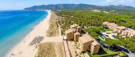A coastal resort with a beach, multiple-story buildings, and a parking area.
