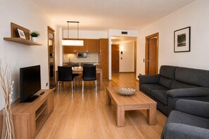 Een moderne woonkamer met een bank, een televisie en een eethoek met stoelen en een tafel.