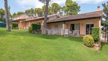 A two-story house with a tiled roof, a front lawn, and a small garden area.