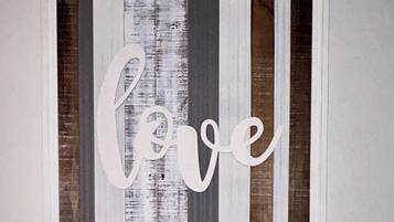 A framed artwork with the word 'love' in a cursive font, set against a background of vertical stripes in varying shades of gray and brown.