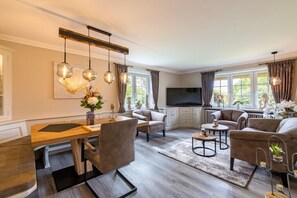 A modern living room with a dining area, a flat-screen TV, and a fireplace. - Country house East Coast (Keitum)