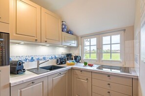 A kitchen with a built-in oven, a coffee maker, and a window with a view of the outdoors. - Country house with south-facing view (Keitum)