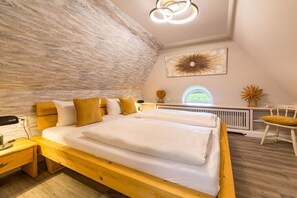 A bedroom with a large bed, a wooden nightstand, a desk, and a chair. - Country house with south-facing view (Keitum)