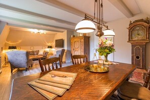 A dining area with a wooden table, chairs, and a chandelier. - Country house with south-facing view (Keitum)