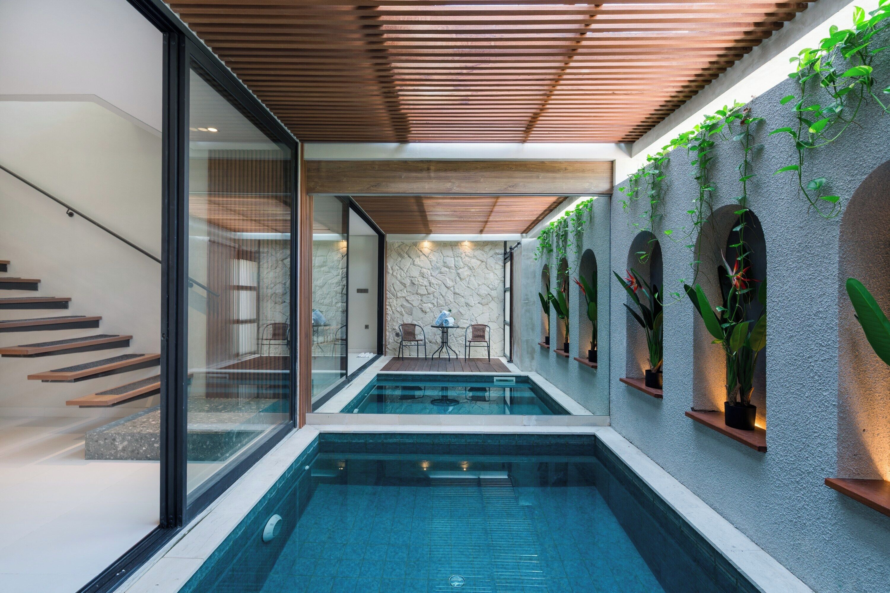Ein moderner, überdachter Pool mit Steinwand und Holzbalkendecke.