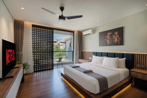 A modern hotel room with a large bed, a ceiling fan, a TV, and a balcony with a view. - Evita Villa by Betterplace (Canggu)