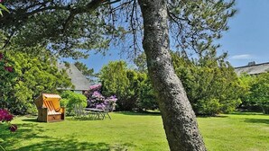 A well-maintained garden with a lawn, a wooden bench, and a small shed. - Country house North Sea (Keitum)