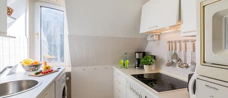 Cocina compacta con lavadora, estufa y lavabo.
